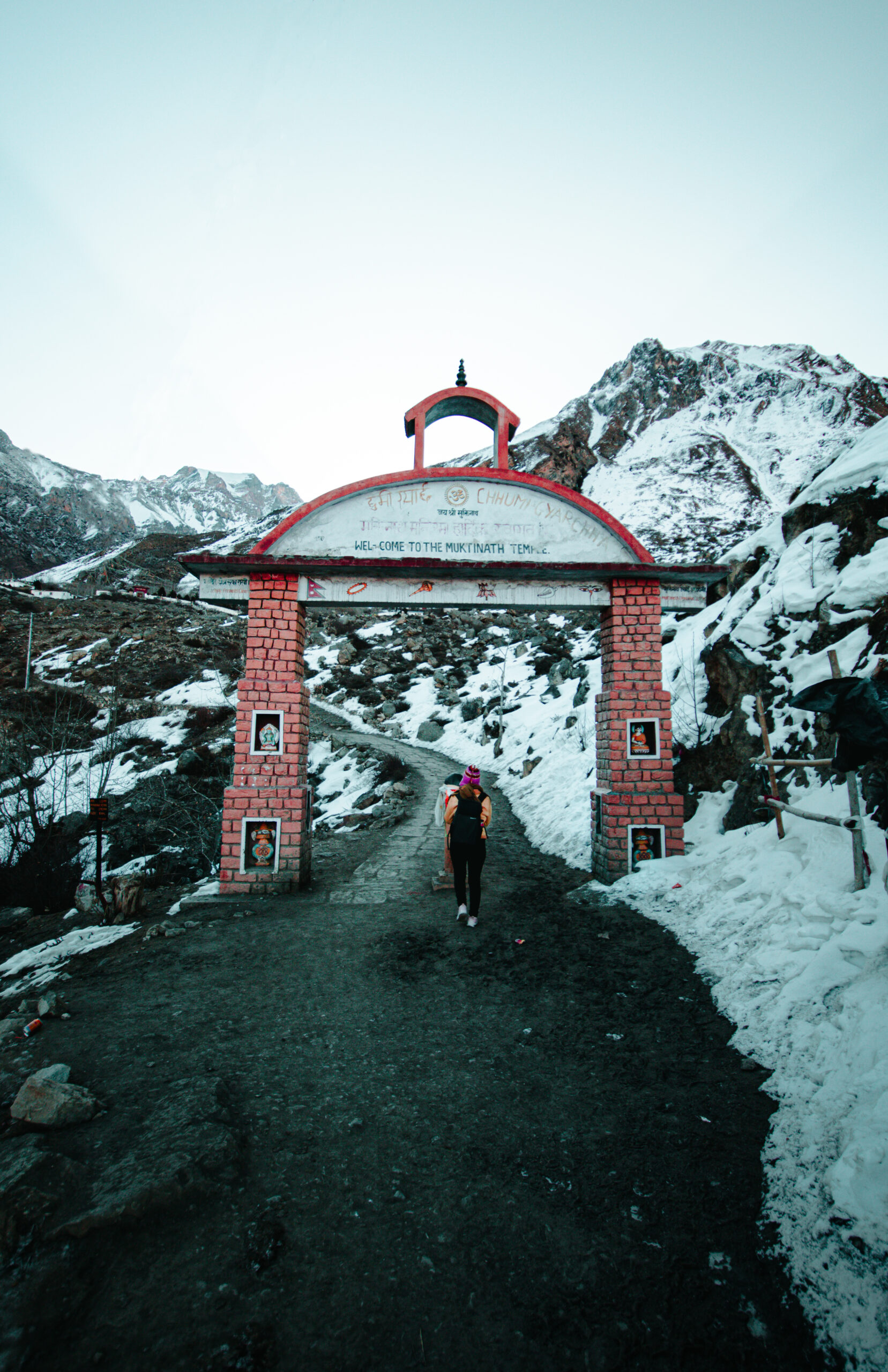 woman walking through brick gate mountainous terrain scaled